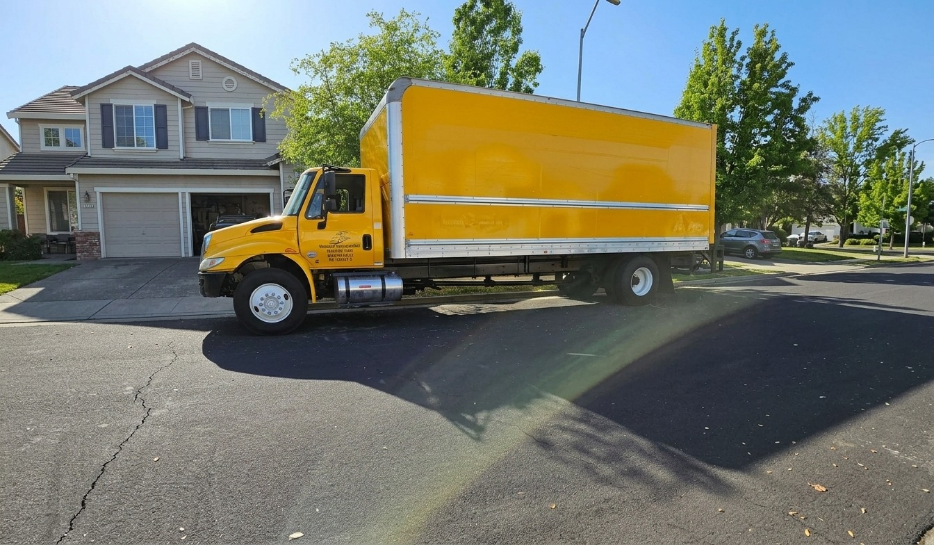Yellow Nmotions box truck parked on a sunny residential street